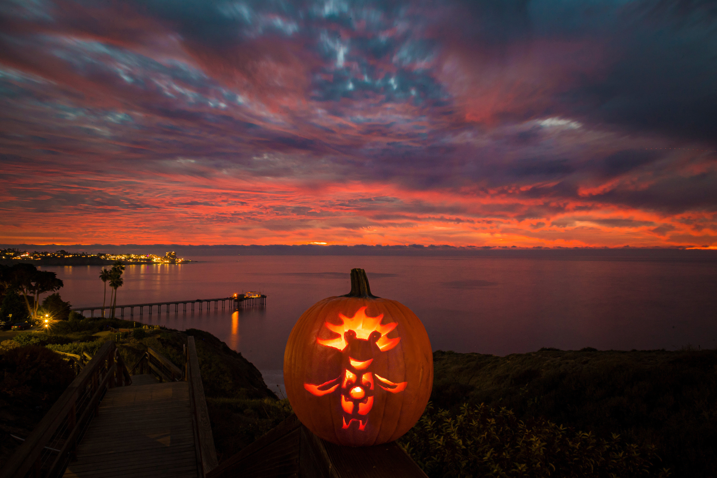 Carved halloween pumpkin in front of Scripps Pier at sunset