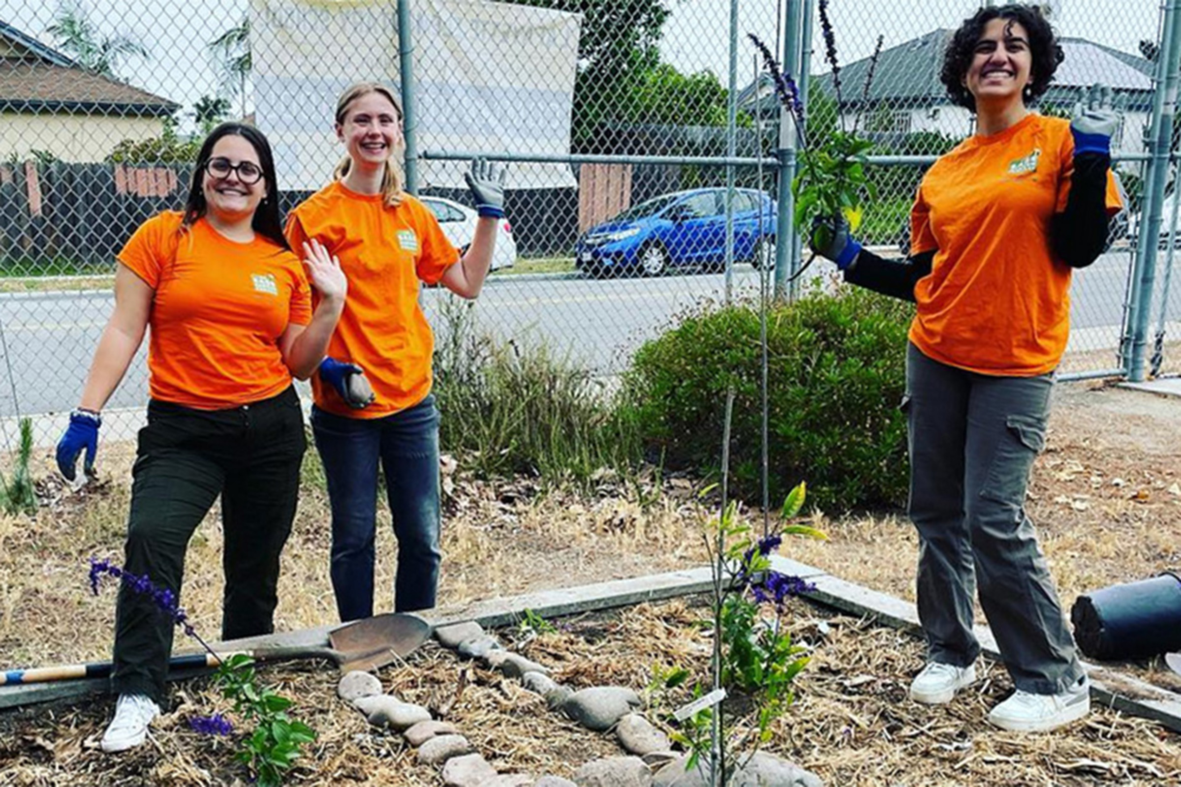 Three students in orange T-shirts work on gardening project